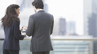 Businesswoman and businessman looking at a tablet on a rooftop.