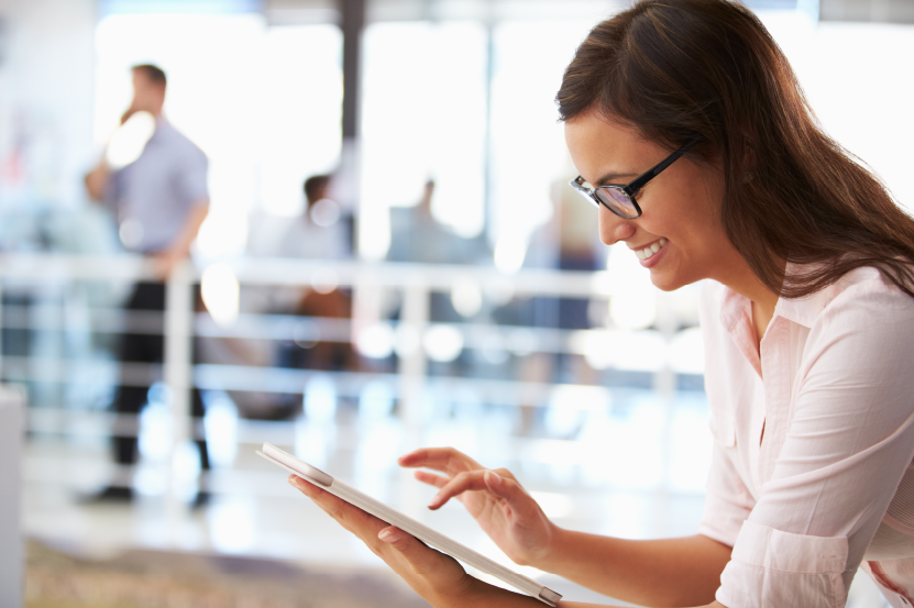 A woman smiling while using her tablet