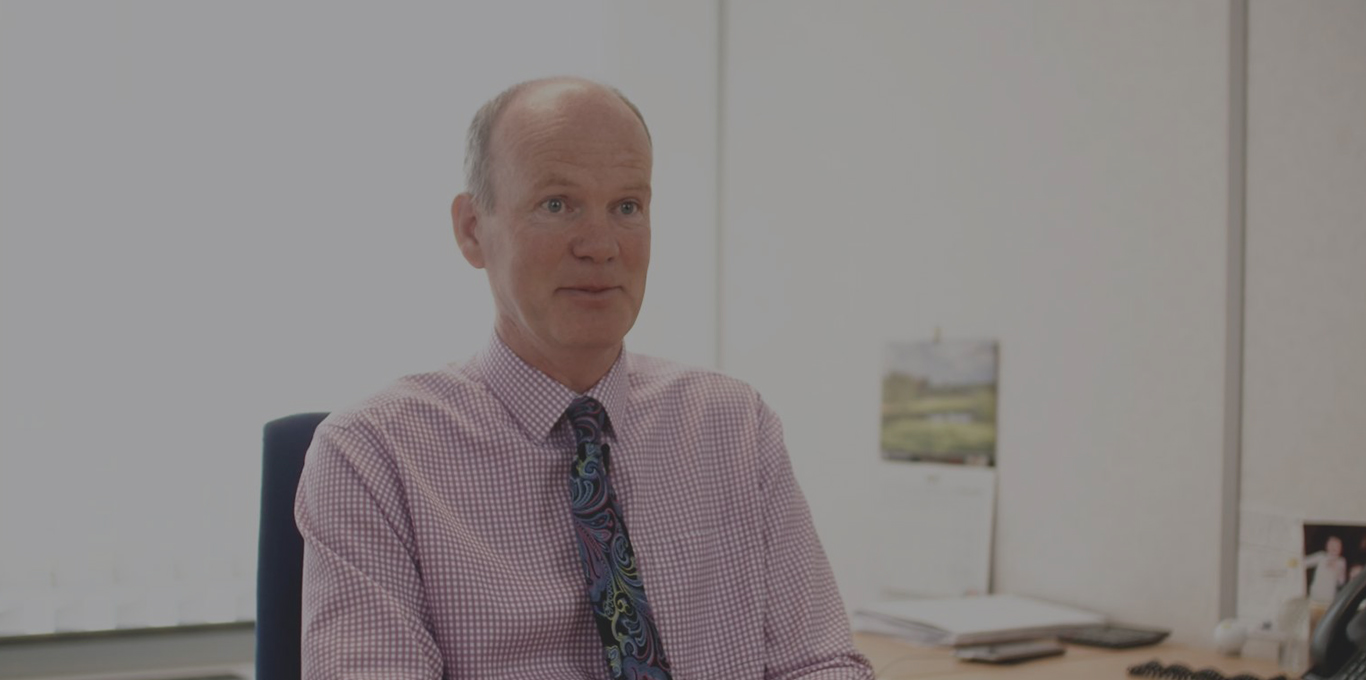 Man in business casual attire sitting in an office.