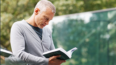 A man reading a book outdoors