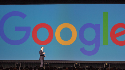 CEO Reid Standing in front of screen with Google logo being displayed.
