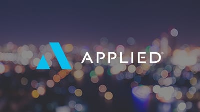 The Applied Systems logo with the word "Applied" next to it in front of a blurred background of a city at nighttime 