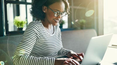 Woman smiling and typing on a laptop.