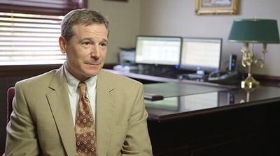 A man in a tan suit sitting in an office